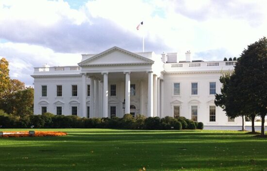 The White House, an iconic neoclassical building with a green lawn and trees.
