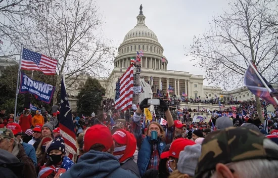 Crowd of supporters gathered at the U.S. Capitol, holding flags and signs during a rally.