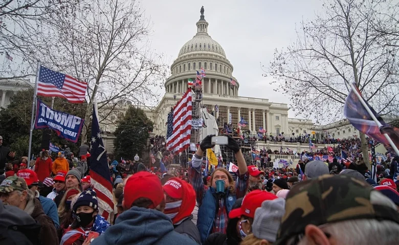 Crowd of supporters gathered at the U.S. Capitol, holding flags and signs during a rally.
