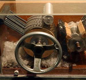 Model of a vintage steam engine with visible gears and moving parts under glass.
