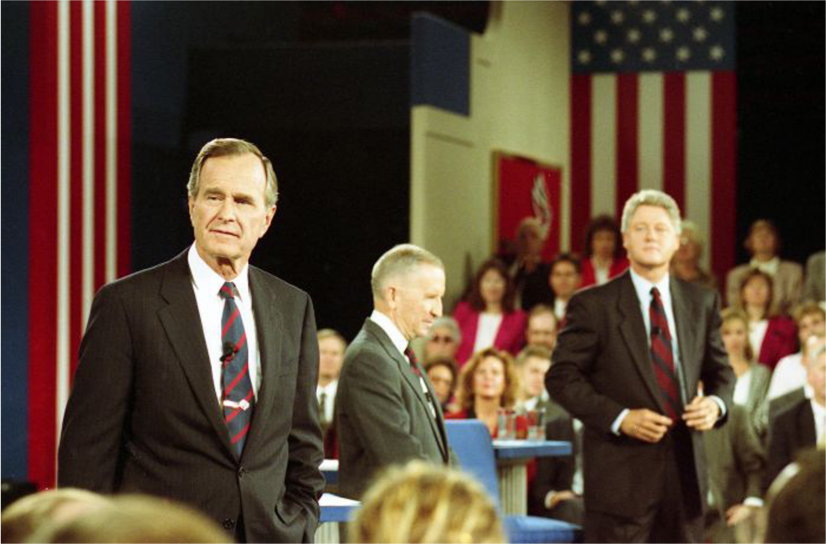 President H.W. Bush, Ross Perot, and Bill Clinton stand on a stage and look out over the crowd.