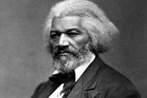 Black and white portrait of a stern-looking man with white hair and a beard, wearing a suit.