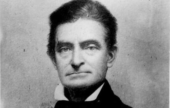 Black and white portrait of a man with a serious expression wearing a suit and collared shirt.