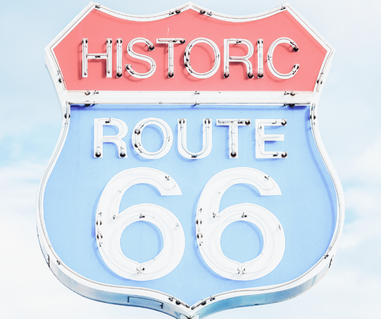 Historic Route 66 sign with a red top and blue background, featuring white lettering and a shield shape.