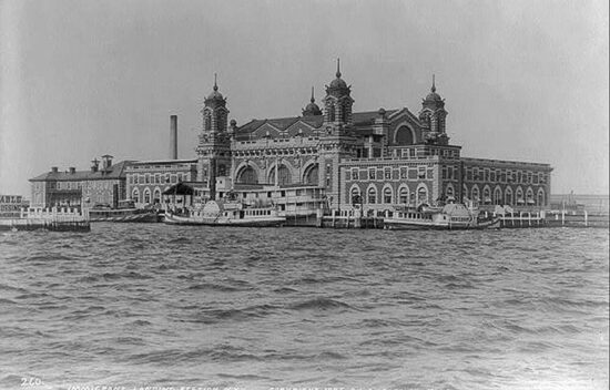 Historic black and white image of Ellis Island Immigration Station viewed from the water.