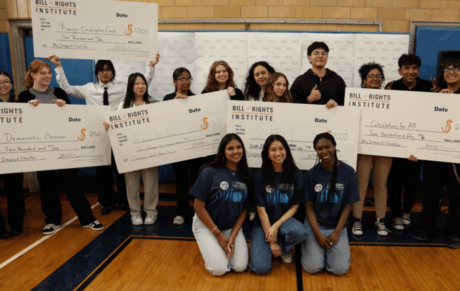 Students and representatives holding large checks for various awards and initiatives at a Bill of Rights Institute event.