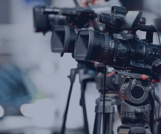 A row of cameras on tripods, positioned for a filming event.