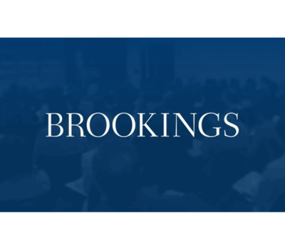 Text "BROOKINGS" on a blue background with an audience blurred in the background.